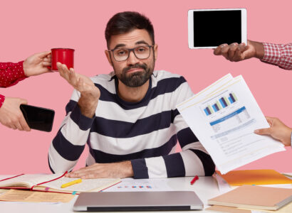 brunet-man-sitting-desk-surrounded-with-gadgets-papers