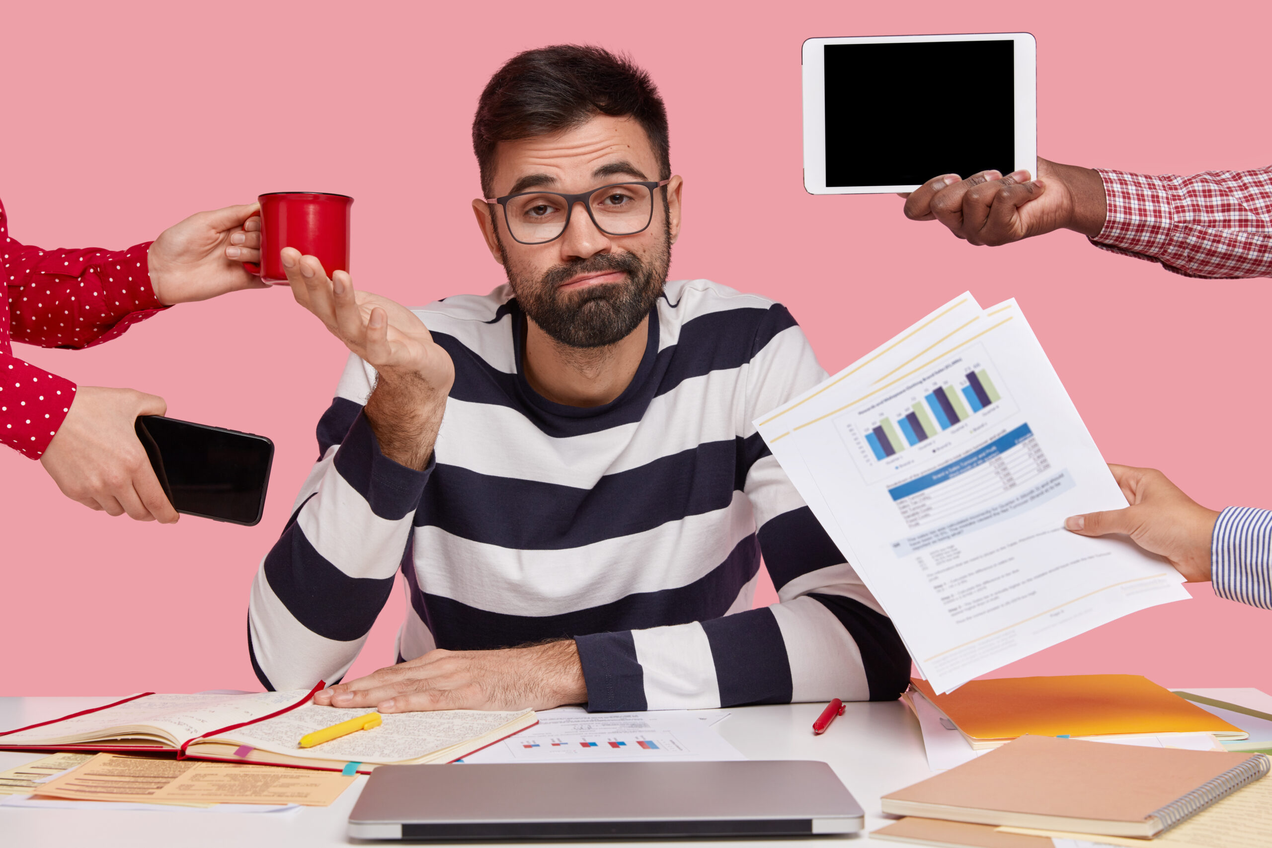 brunet-man-sitting-desk-surrounded-with-gadgets-papers