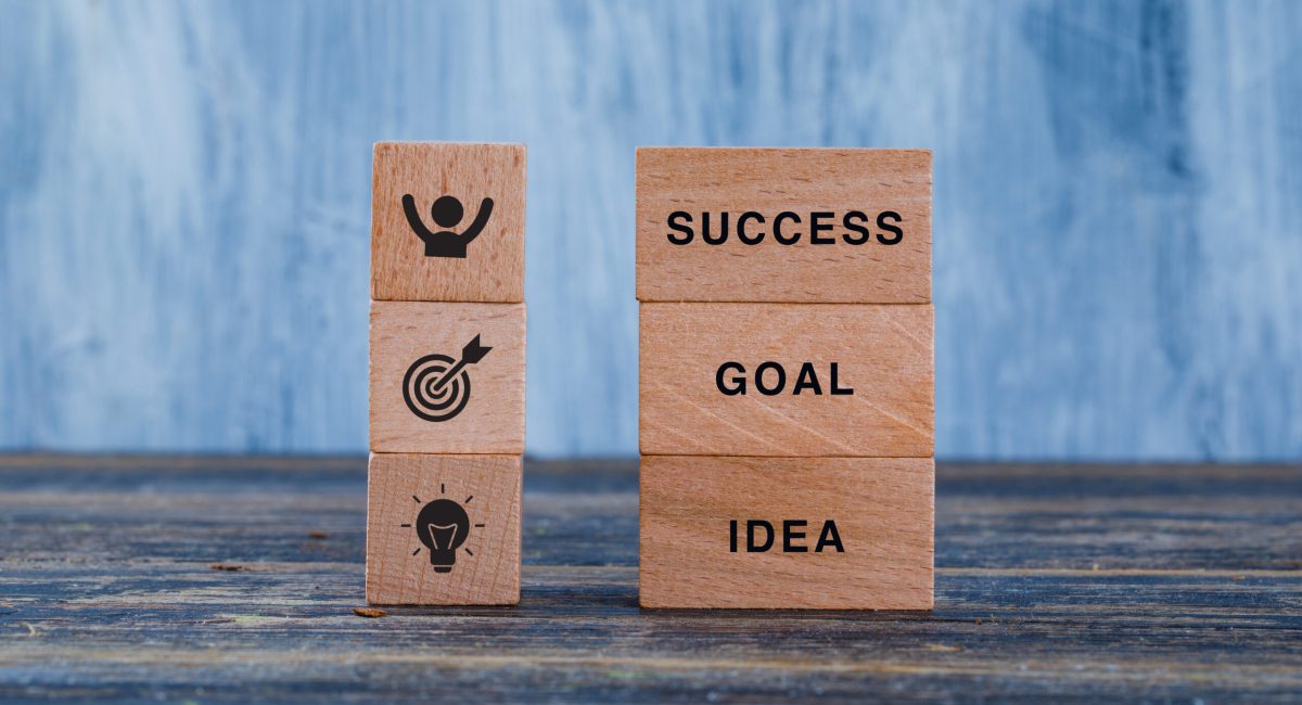 Business strategy concept with wooden blocks on wooden and grungy blue background side view.